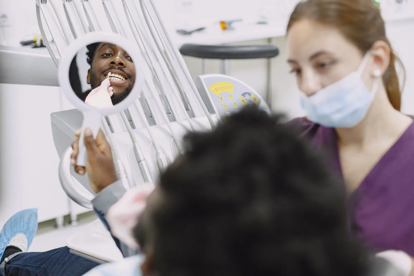 Patient looking at his smile in a dental mirror during a professional consultation