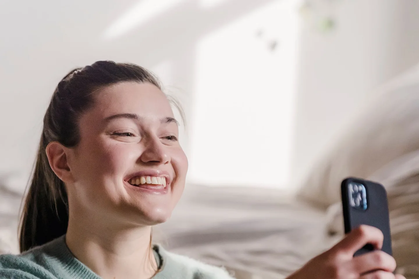 Woman taking a clear tooth-showing smile photo with a smartphone at home