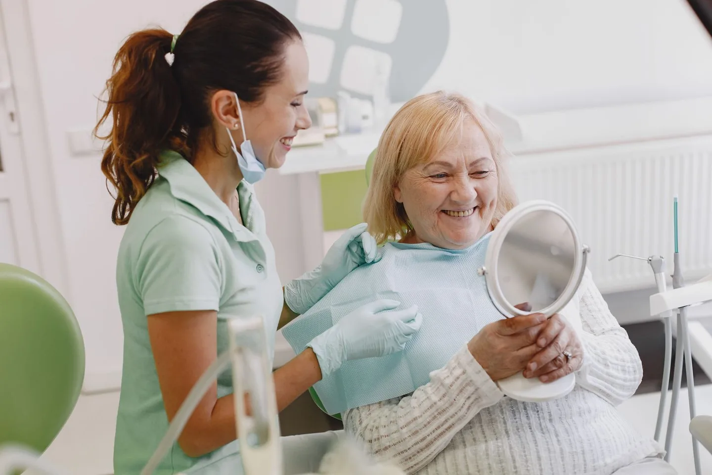 Patient reviewing her smile in a mirror with a dental professional