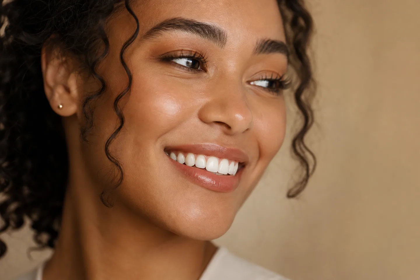 Woman with a natural, proportionate smile in warm studio light